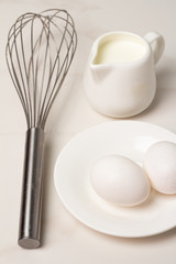 eggs and whisk on a white plate