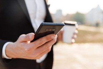 Close up of a businessman using mobile phone outdoors
