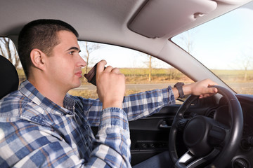 man drinking coffee while driving a car