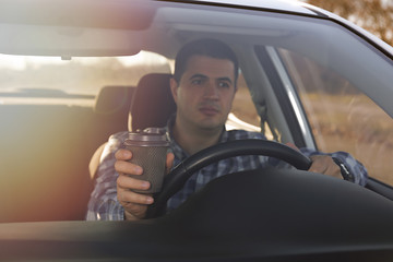 man drinking coffee while driving a car