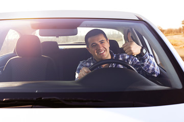 Young man doing thumps-up in car