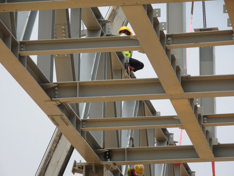 Construction workers working at height installing the steel structure. Steel structure able to provide huge and long span for the building.