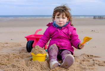 cute little girl playing on the beach in autumn or spring