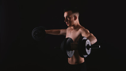 Fototapeta na wymiar Photo of young man doing exercise with dumbbells over dark background