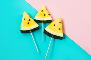 cut off triangular slices of ripe yellow watermelon on pink-blue background