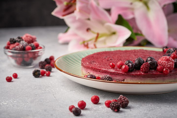 Raw vegan berry cherry cheesecake gluten-free on grey background.
