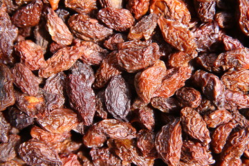 black raisins in the wooden bowl. Sweet dry raisins close-up shot for background . Many Raisins for background grape raisin texture .