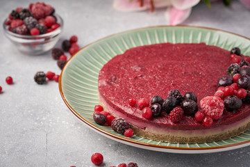 Raw vegan berry cherry cheesecake gluten-free on grey background.