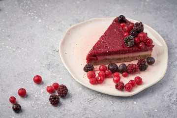 Raw vegan berry cherry cheesecake gluten-free on grey background.