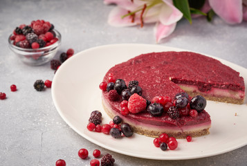 Raw vegan berry cherry cheesecake gluten-free on grey background.