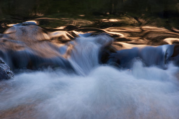 Landscape of the Merced River illuminated with reflected golden color from sunlit cliffs at sunrise...