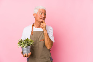 Middle aged gardener man isolated looking sideways with doubtful and skeptical expression.