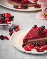 Raw vegan berry cherry cheesecake gluten-free on grey background.