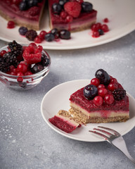 Raw vegan berry cherry cheesecake gluten-free on grey background.