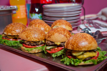 Beautifully decorated catering banquet table with different hamburgers burgers sandwiches on a plate on corporate birthday . Mini or Small Burger Canape in Luxury Restaurant for Brunch Time .