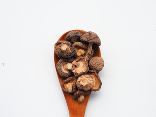 Dried Shiitake Mushrooms on wooden spoon on white wooden table, is an edible mushroom native to East Asia, Mushroom is cultivated and consumed in many Asian countries.
