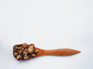 Dried Shiitake Mushrooms on wooden spoon on white wooden table, is an edible mushroom native to East Asia, Mushroom is cultivated and consumed in many Asian countries.