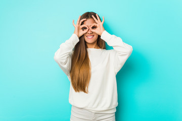 Fototapeta premium Young slim woman showing okay sign over eyes