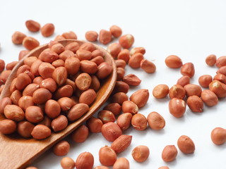 Peanut beans on wooden spoon and white wooden background, is a legume crop grown mainly for its edible seeds, Selective focus.
