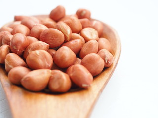 Peanut beans on wooden spoon and white wooden background, is a legume crop grown mainly for its edible seeds, Selective focus.