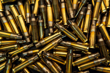 Background from empty cartridges for rifles and carbines. Shiny brass shells scattered on the...