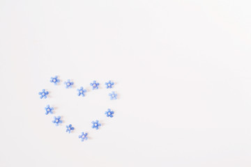 Blue forget-me-nots in the shape of a heart. Small flowers on a white background, holiday card