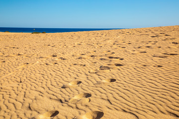 Footsteps on Sand light blue heaven sky dark blue sea Sand on the beach forms structures shapes on golden yellow fine sand background pattern holiday season summer travel vacation abstract line wave