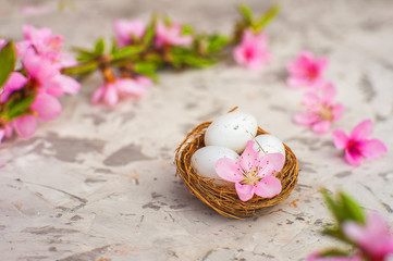 Spring conceptual photo with flowers. Flat lay blooming tree, easter eggs. The tree blooms pink and the eggs in the nest and copy space.