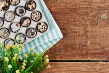 Quail eggs on wooden table close-up. Festive decoration with flowers for Easter with empty copy space for your text.