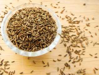 cumin in a glass cup on a wooden table