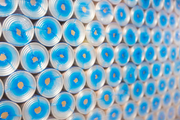Covers for tin cans, packed in blue tubes, background, texture for production, manufacture. Side view