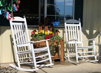 Rustic, country style front porch seating with white rocking chairs and fresh flowers