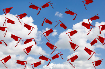 airborne red graduation hats with tassels in summer blue sky
