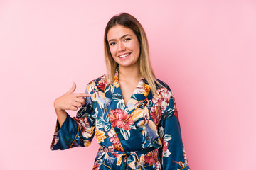 Young caucasian woman wearing pajamas person pointing by hand to a shirt copy space, proud and confident