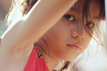 Portrait image of sad little Asian girl.Head shot of 6-7 years old Asian girl with brunette and brown hair looking to the camera.Girl look sad or upset. 