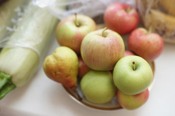 whole apples on a plate and zucchini on the table.