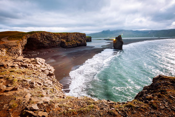 View on Kirkjufjara beach and Arnardrangur cliff. Location Atlantic ocean, Iceland, Europe.