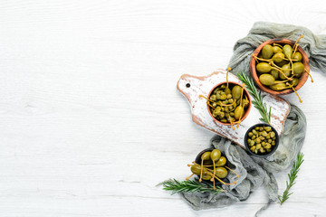 Marinated capers in a bowl on a white wooden background. Top view. Free space for your text.