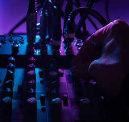 Close up view of audio mixing desk in music studio with one hand moving knobs, music concept