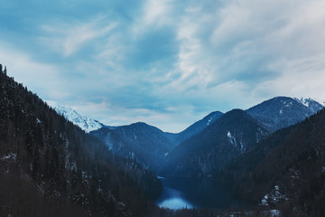 Winter lake Ritsa in Abkhazia with mountains in the snow in the background, late evening.