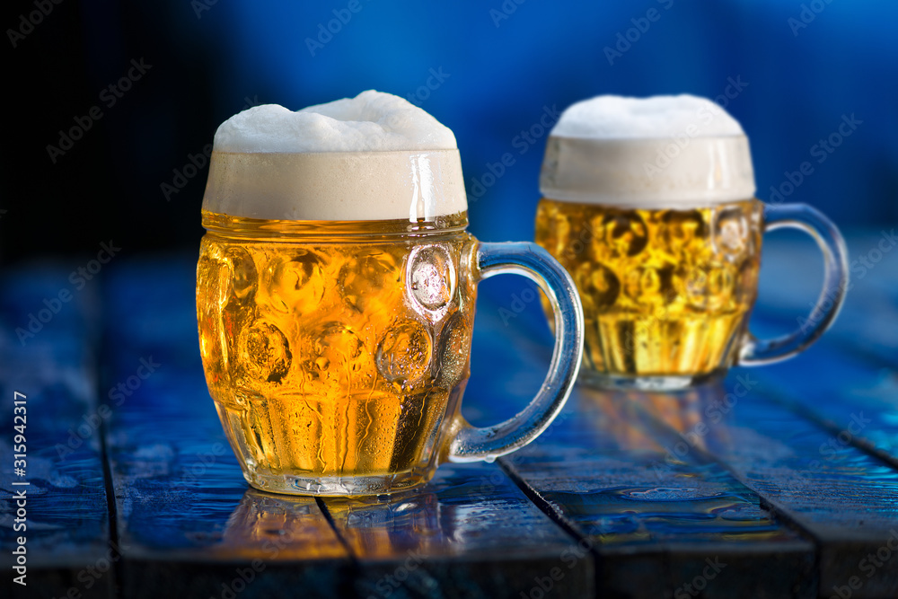 Wall mural Glasses of beer on the blue wooden background.