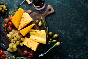 Wine, cheese and snacks on a black stone background. Assorted cheese. Top view. Free space for your text.