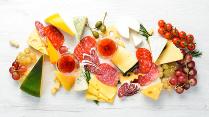 Italian antipasti wine snacks set. Cheese variety, salami and grapes on a white wooden background. Italian cuisine. Top view. Free space for your text.