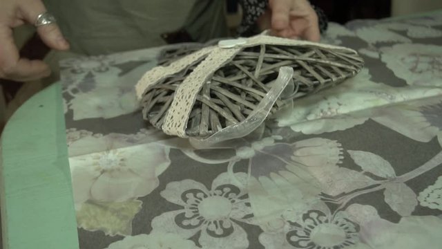 Cheerful female florist cutting wrapping paper with scissors at the table while making beautiful flower bouquet arrangement in flower shop for a gift. Florist preparing paper for packaging flowers.