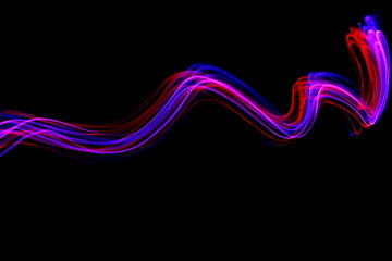 Long exposure light painting, vibrant purple and red color in abstract swirl against a clean black background.  Light painting photography.