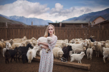 girl in the arms of a lamb farm in the mountains