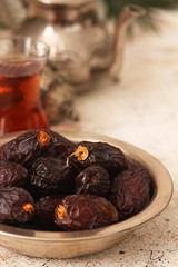 Fresh Medjool Dates in a bowl with tea on light  background. Ramadan kareem.