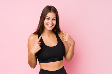 Fototapeta na wymiar Young caucasian fitness woman doing sport isolated smiles, pointing fingers at mouth.