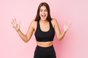 Young caucasian fitness woman doing sport isolated receiving a pleasant surprise, excited and raising hands.