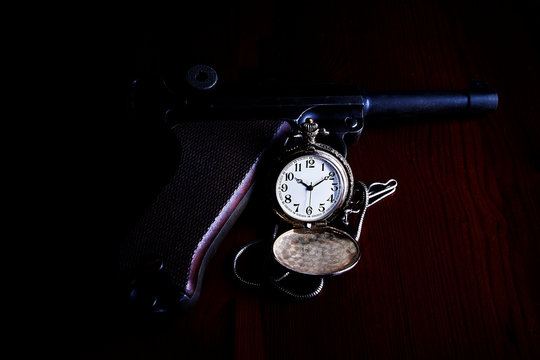 Reloj de bolsillo con pistola y fondo oscuro